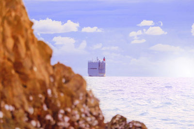 Lighthouse on rock by sea against sky