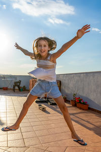 Full length of happy boy jumping against sky