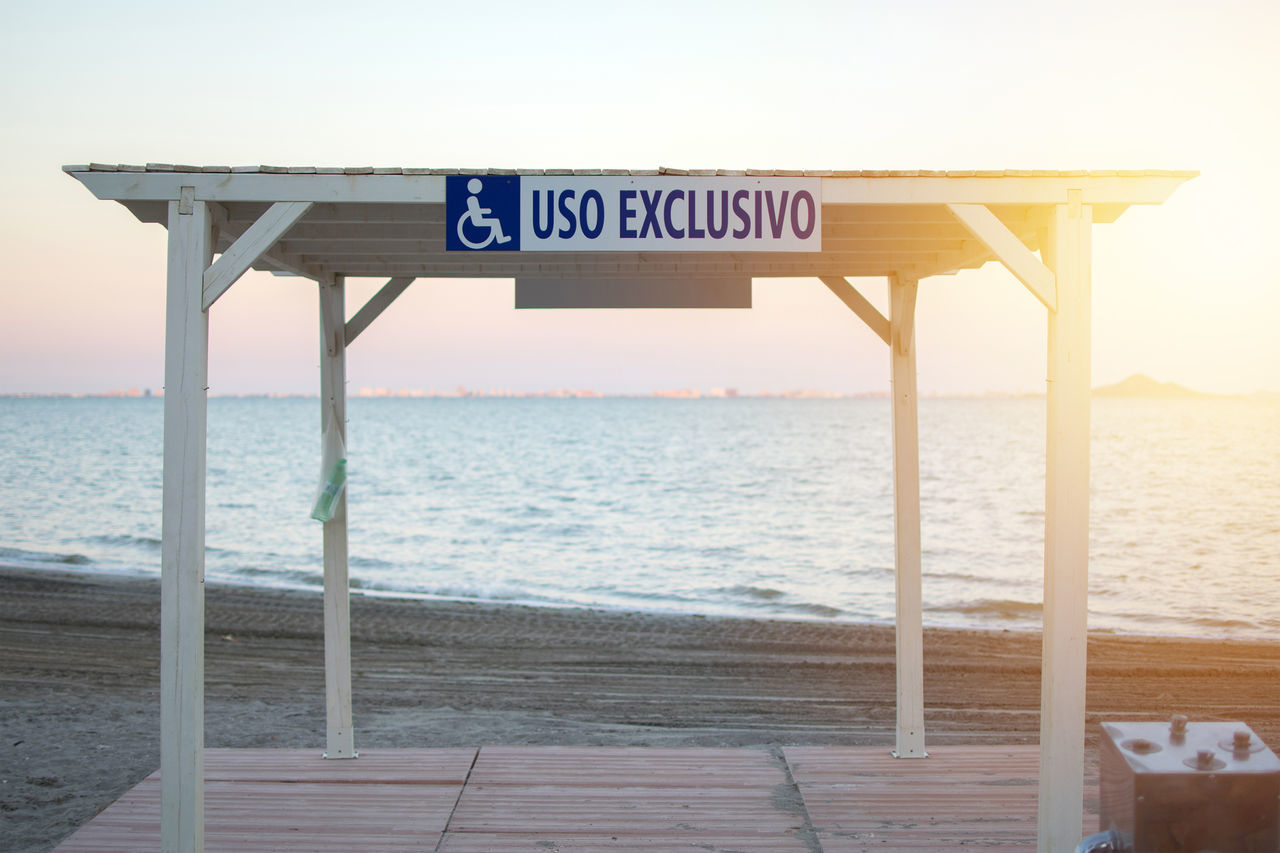 INFORMATION SIGN ON BEACH AGAINST SKY