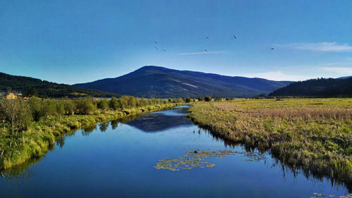 Scenic view of lake and mountains against blue sky