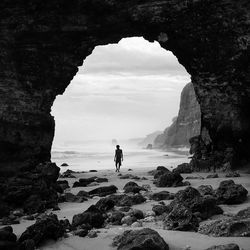 Man standing on cliff by sea against sky