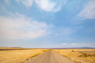 Road amidst field against sky