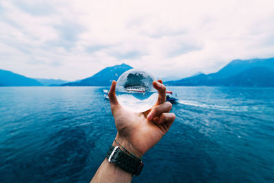 Close-up of hand holding sea against sky