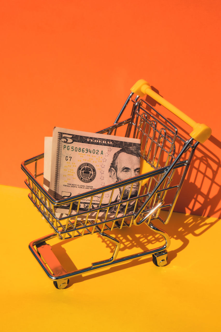 shopping cart, colored background, consumerism, shopping, studio shot, finance, retail, vehicle, no people, orange color, metal, indoors, business, yellow, wealth, currency, buying, technology