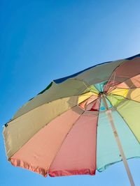 Low angle view of multi colored umbrella against clear blue sky