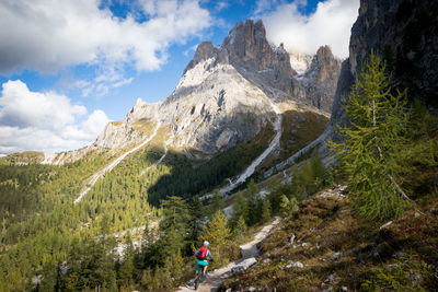 Woman cycling of mountain road against cloudy sky