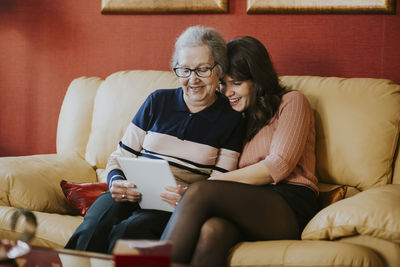 Granddaughter and grandmother watching something on the table