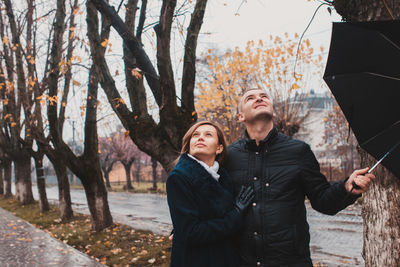 Young couple standing by trees during autumn