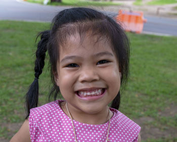 Portrait of little adorable asian girl smiling and looking at camera in a park at day time. 