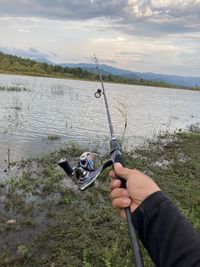 Man fishing in water against sky