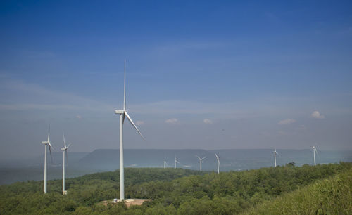 Wind turbines on field against sky