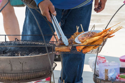 Midsection of man preparing food on barbecue grill