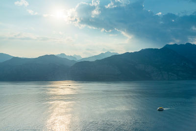 Scenic view of sea and mountains against cloudy sky