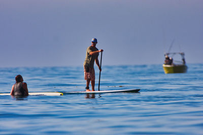 Rear view of men on boat in sea against sky