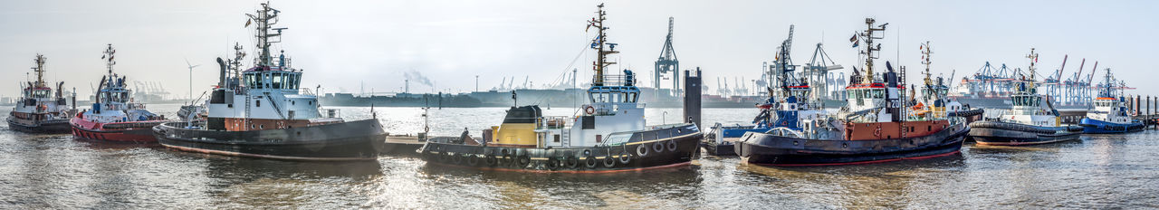 Boats moored at harbor against sky