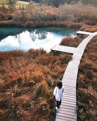 Rear view of woman standing by lake