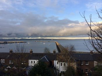 Houses and buildings by sea against sky