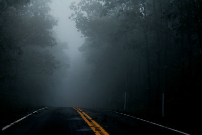 Road amidst trees in forest during rainy season