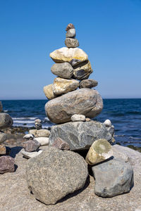 Stack of stones in sea against clear sky