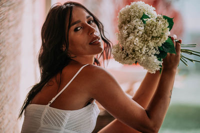 Portrait of beautiful woman holding red flowering plant