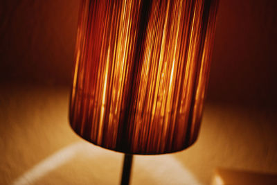 Close-up of illuminated lamp on table against wall