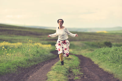 Full length of woman running on field against sky