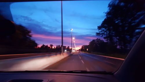 Cars on road against sky seen through car windshield