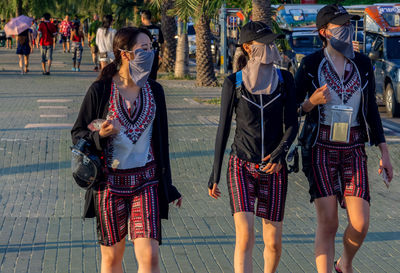 Rear view of people walking on street in city