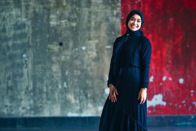 Beautiful indonesian woman wearing a black hijab against the rustic wall as a background