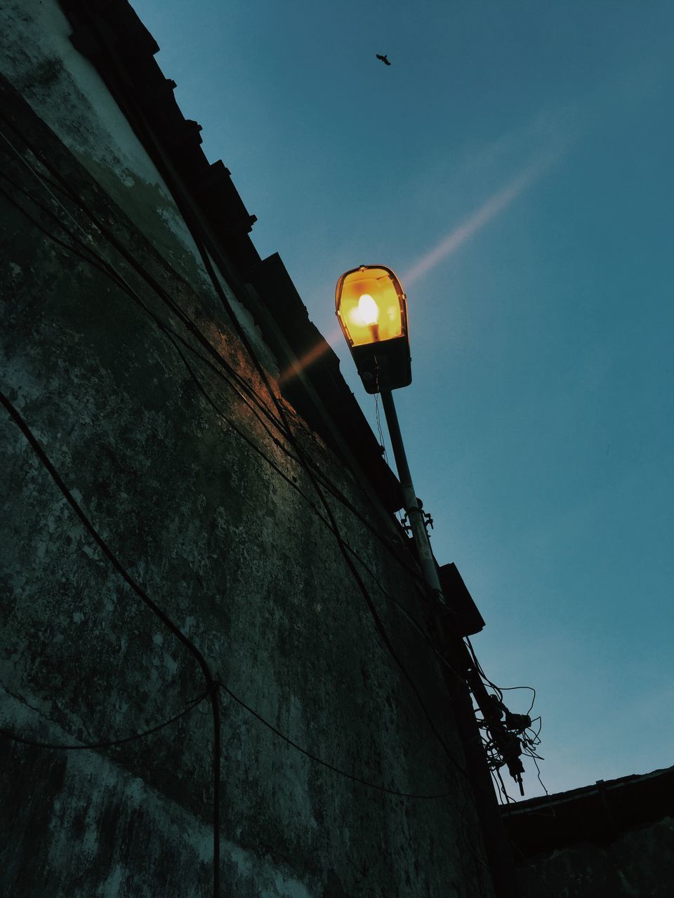 LOW ANGLE VIEW OF ILLUMINATED STREET LIGHT BY BUILDING