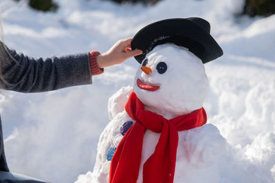Caucasian woman sculpts a snowman from the snow. the carrot is the place of the nose