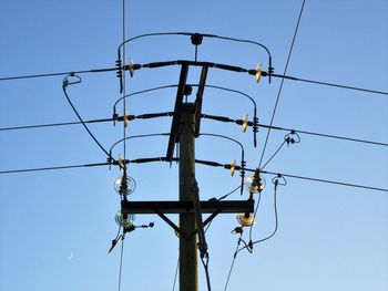 Low angle view of electricity pylon against clear sky