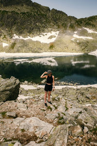 Rear view of man standing on rock by lake