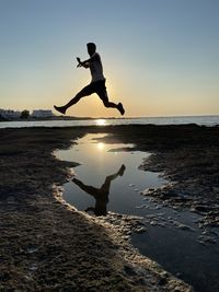 Rear view of man standing on rock against sky