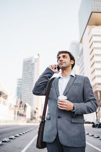 Businessman talking on phone while standing on road