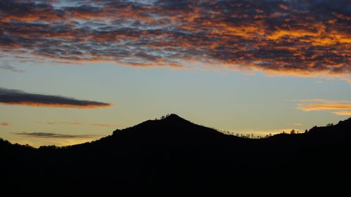 Silhouette mountain against dramatic sky during sunset