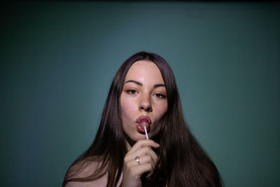 Portrait of beautiful young woman licking lollipop