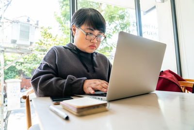 Young man using mobile phone while sitting on table