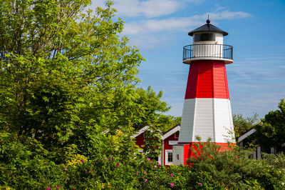 Low angle view of lighthouse by building against sky