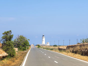 Road amidst trees against clear blue sky