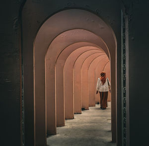Rear view of man walking in tunnel