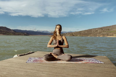 Young woman with hands clasped meditating on sunny day