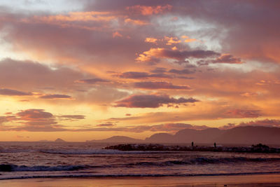 Scenic view of sea against dramatic sky during sunset