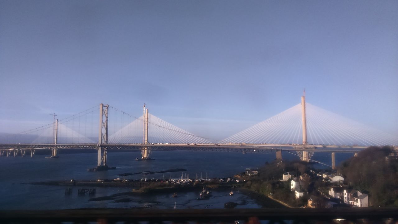 bridge - man made structure, suspension bridge, connection, transportation, sky, built structure, architecture, water, engineering, no people, illuminated, outdoors, sea, city, bridge, nature, day