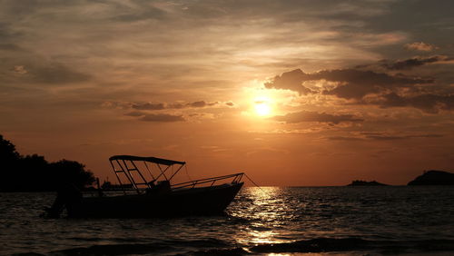 Silhouette fishing boat in sea against sky during sunset