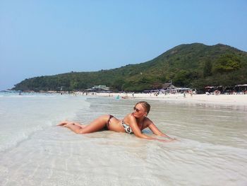 Young woman on beach against clear sky