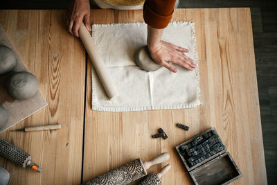 Female potter preparing clay for modelling on table, top view