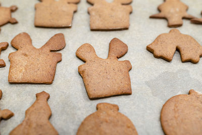 Baked gingerbread cookies in various shapes without decorations, lying on baking paper.