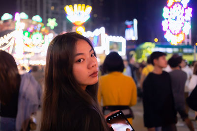 Portrait of smiling young woman in amusement park at night