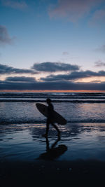 Silhouette person on beach against sky during sunset